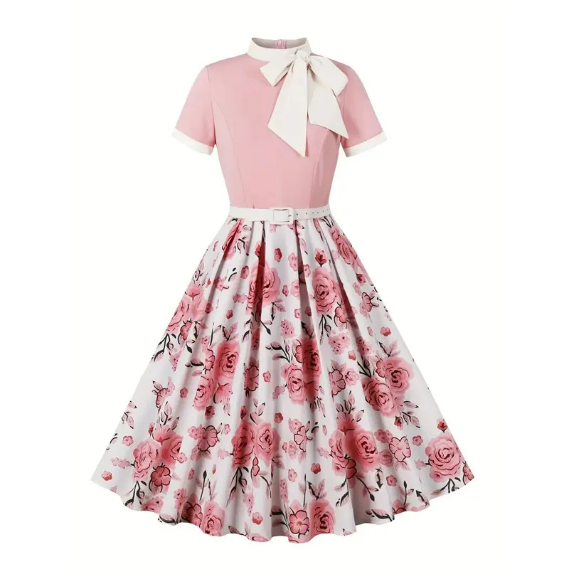 Screenshot of a real dress. A vintage-style dress with a pink fitted top, short sleeves, a large white bow at the neck, and a white flared skirt featuring a pink rose floral pattern. The dress has a matching white belt at the waist.